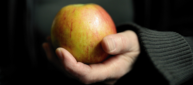 Hand håller i ett äpple - äpple är bra för mage och tarm